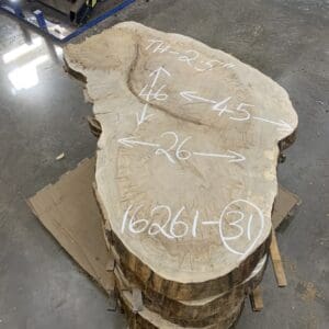 Stacked wooden slabs with measurements written in chalk.