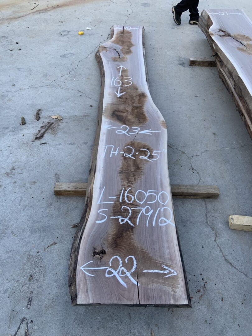 A large wooden slab with markings and numbers on a concrete floor.